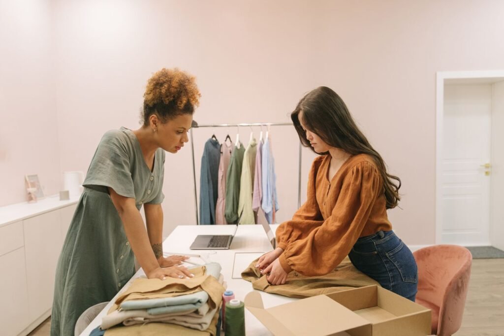 Two young women working together in a modern boutique, organizing clothes with focus and style.